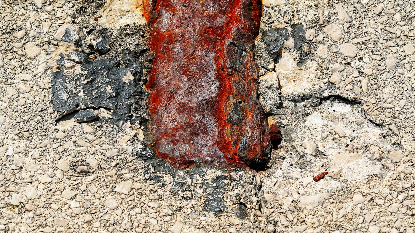Close-up of cracked concrete with heavily rusted exposed rebar and spalling